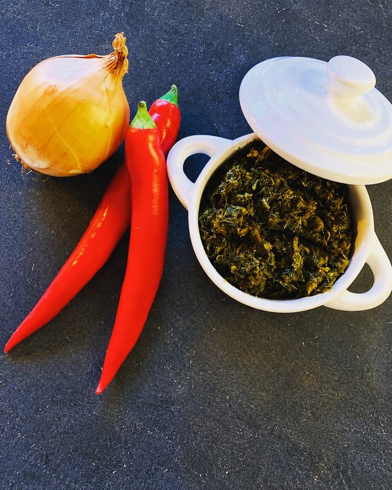 Pondu servi dans une petite cocotte blanche, à côté de piments rouges et d'un oignon